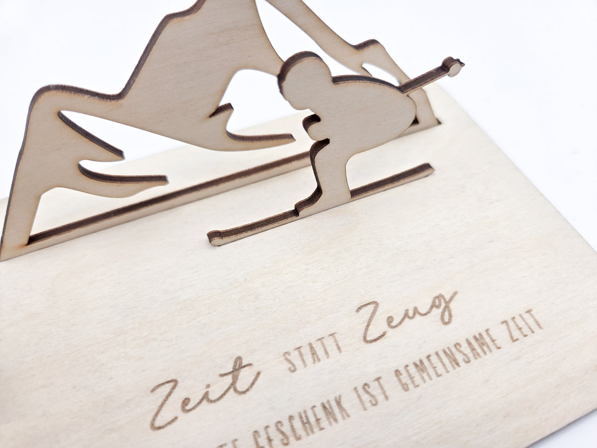 Geschenkkarte aus Holz mit filigranem Skifahrer vor einer Bergkulisse und der Gravur „Zeit statt Zeug – Das schönste Geschenk ist gemeinsame Zeit“. Die besondere Holzkarte eignet sich ideal als Geldgeschenk für Skiurlaub, Skitag oder Winterurlaub sowie als Gutschein für gemeinsame Erlebnisse. Eine kreative Geschenkidee für Skifahrer, Bergliebhaber, Paare, Freunde und Familie zu Geburtstag, Weihnachten oder Jahrestag – natürlich und liebevoll gestaltet.