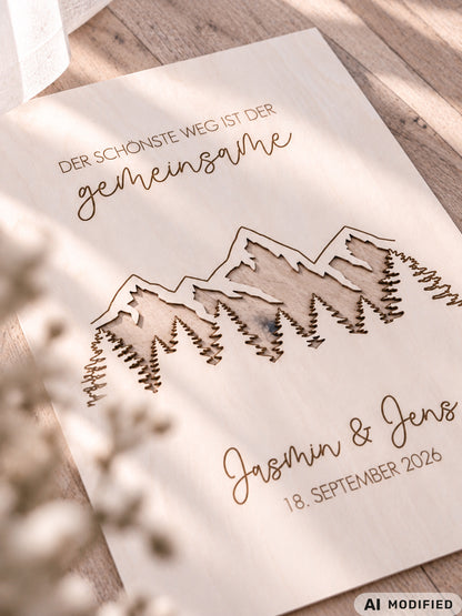 Personalisiertes Geldgeschenk zur Hochzeit aus Holz mit filigran ausgeschnittener Berg- und Waldlandschaft. Hinter den Bergen lassen sich Geldscheine dekorativ platzieren. Mit Gravur „Der schönste Weg ist der gemeinsame“, Namen des Brautpaares und Hochzeitsdatum. Originelles Hochzeitsgeschenk für Braut und Bräutigam, ideal als Geldgeschenk zur Hochzeit, personalisierte Hochzeitsdeko und besondere Geschenkidee für Paare, Bergliebhaber, Wanderfreunde und Naturliebhaber.