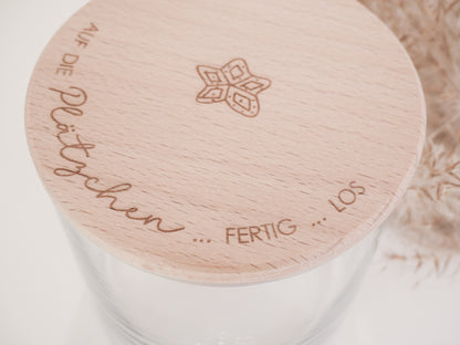 Glas mit Holzdeckel und Gravur „Auf die Plätzchen … fertig … los“ gefüllt mit Weihnachtsplätzchen. Daneben liegen Zimtsterne und Vanillekipferl auf hellem Hintergrund – stimmungsvolles, nordisch-cleanes Weihnachtsmotiv.