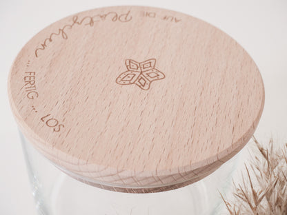 Glas mit Holzdeckel und Gravur „Auf die Plätzchen … fertig … los“ gefüllt mit Weihnachtsplätzchen. Daneben liegen Zimtsterne und Vanillekipferl auf hellem Hintergrund – stimmungsvolles, nordisch-cleanes Weihnachtsmotiv.