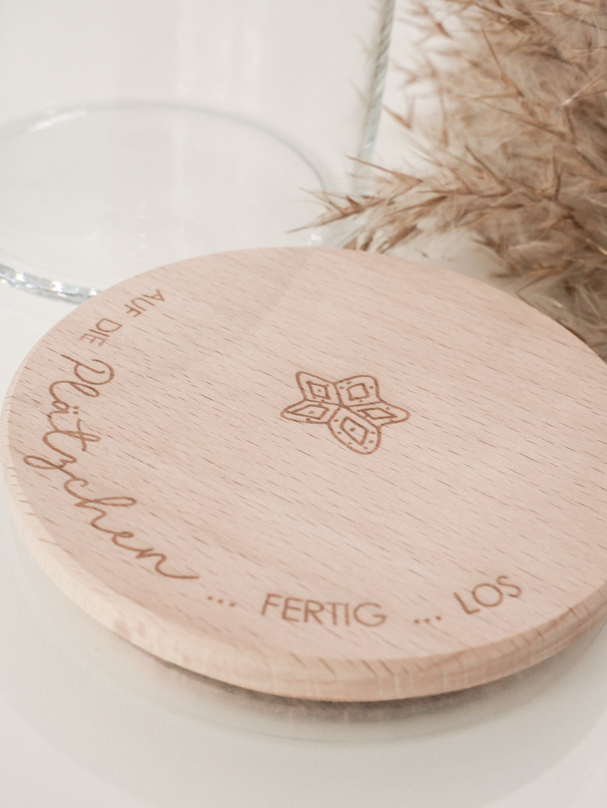 Glas mit Holzdeckel und Gravur „Auf die Plätzchen … fertig … los“ gefüllt mit Weihnachtsplätzchen. Daneben liegen Zimtsterne und Vanillekipferl auf hellem Hintergrund – stimmungsvolles, nordisch-cleanes Weihnachtsmotiv.