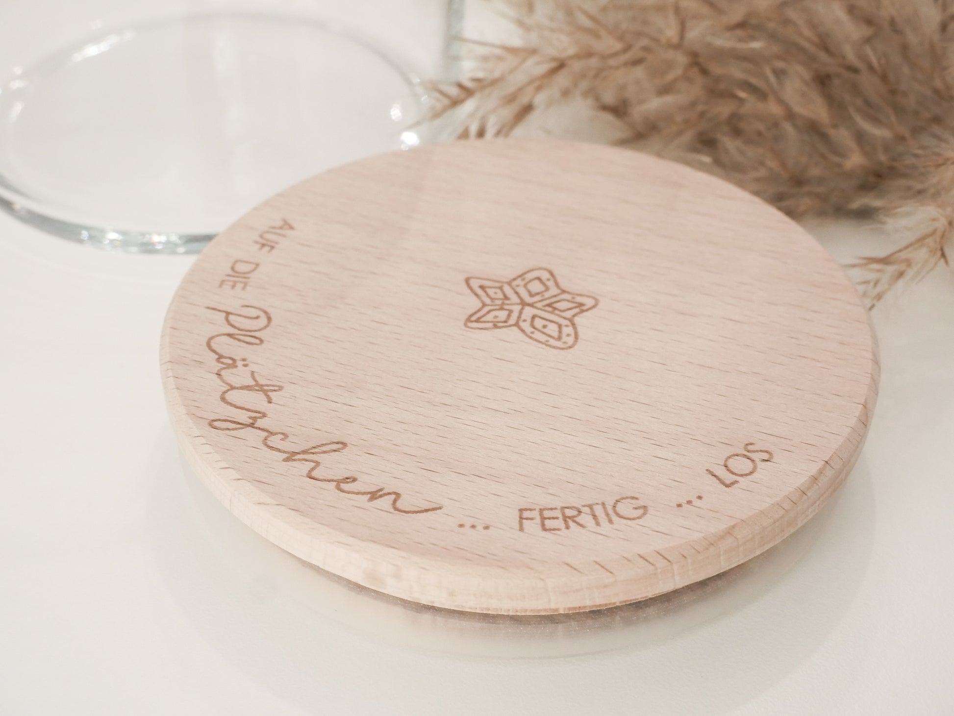 Glas mit Holzdeckel und Gravur „Auf die Plätzchen … fertig … los“ gefüllt mit Weihnachtsplätzchen. Daneben liegen Zimtsterne und Vanillekipferl auf hellem Hintergrund – stimmungsvolles, nordisch-cleanes Weihnachtsmotiv.