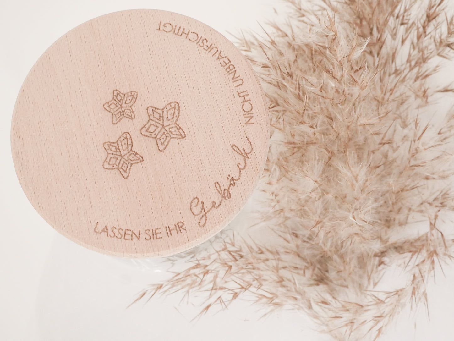 Handgefertigtes Vorratsglas mit graviertem Holzdeckel und Aufschrift „Lassen Sie Ihr Gebäck nicht unbeaufsichtigt“, dekoriert mit feinen Schneeflocken. Ein liebevolles Detail für jede Küche – natürlich, stilvoll und von Leo & Lu.