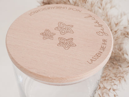 Handgefertigtes Vorratsglas mit graviertem Holzdeckel und Aufschrift „Lassen Sie Ihr Gebäck nicht unbeaufsichtigt“, dekoriert mit feinen Schneeflocken. Ein liebevolles Detail für jede Küche – natürlich, stilvoll und von Leo & Lu.