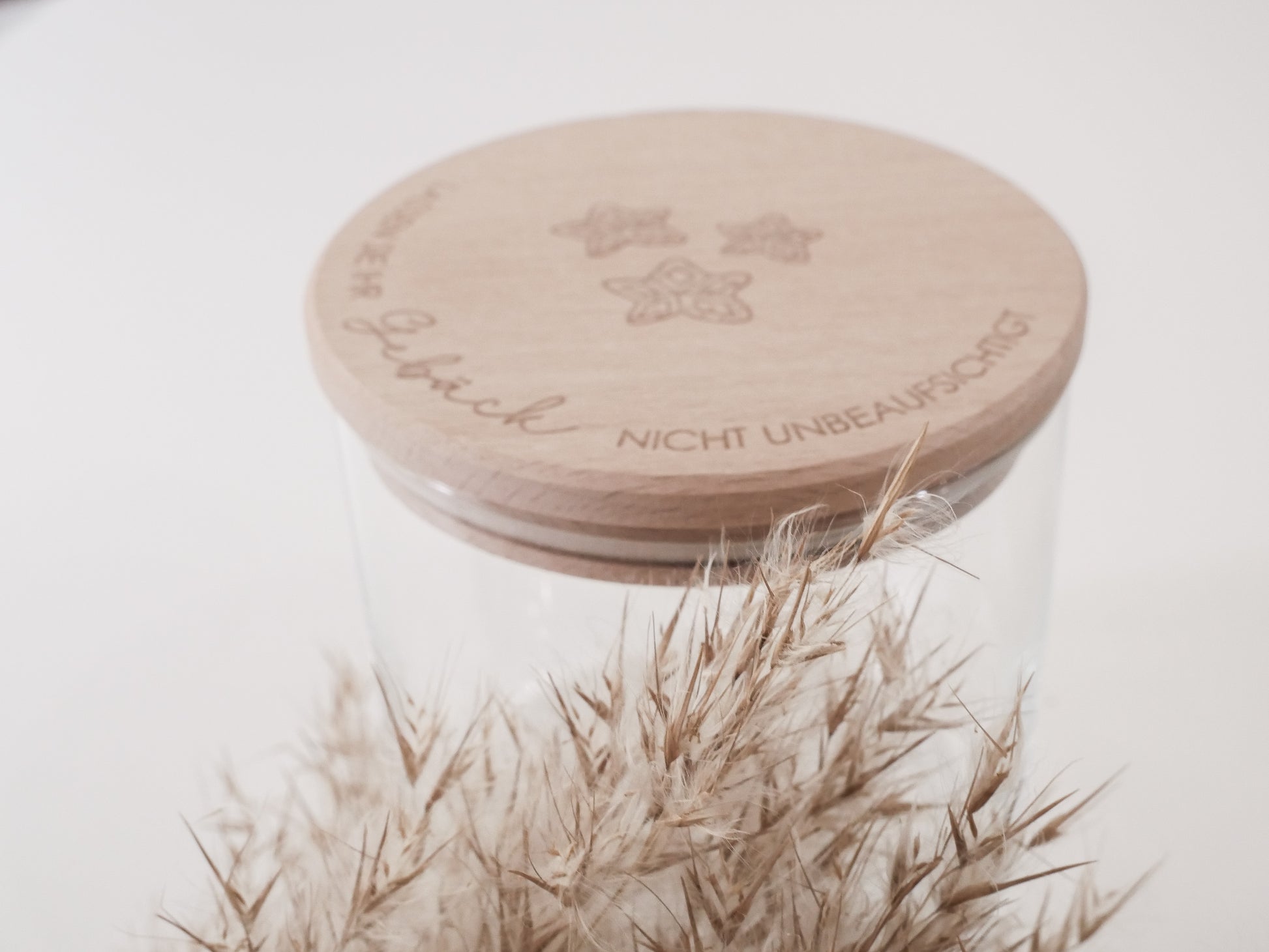 Handgefertigtes Vorratsglas mit graviertem Holzdeckel und Aufschrift „Lassen Sie Ihr Gebäck nicht unbeaufsichtigt“, dekoriert mit feinen Schneeflocken. Ein liebevolles Detail für jede Küche – natürlich, stilvoll und von Leo & Lu.