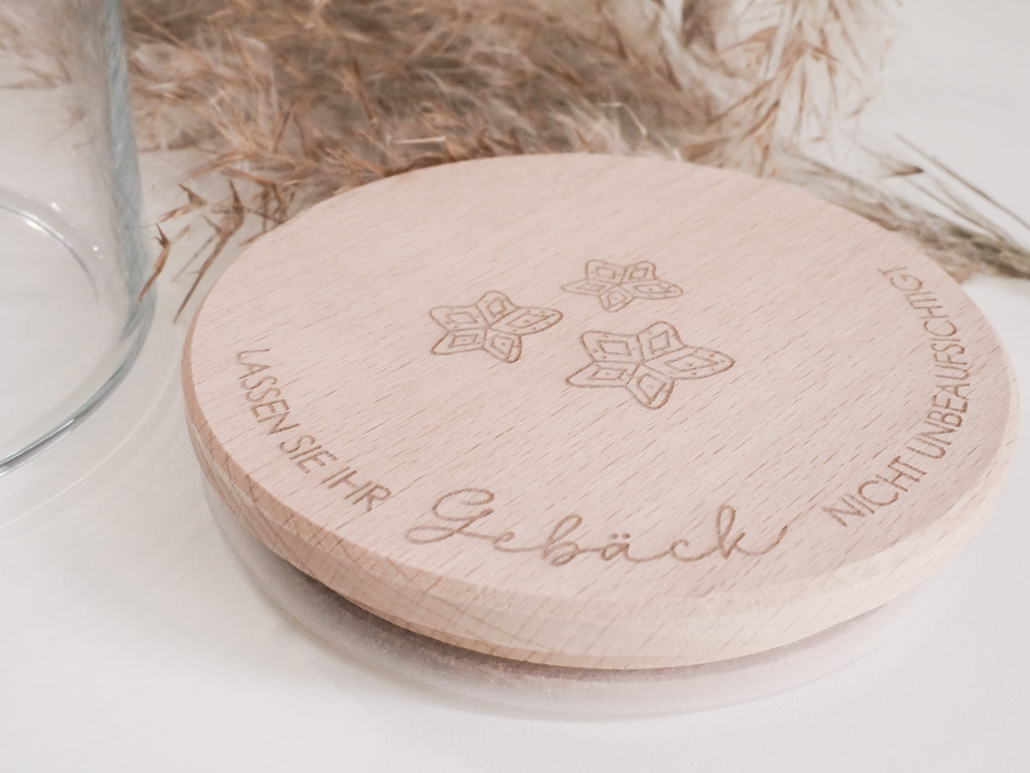Handgefertigtes Vorratsglas mit graviertem Holzdeckel und Aufschrift „Lassen Sie Ihr Gebäck nicht unbeaufsichtigt“, dekoriert mit feinen Schneeflocken. Ein liebevolles Detail für jede Küche – natürlich, stilvoll und von Leo & Lu.