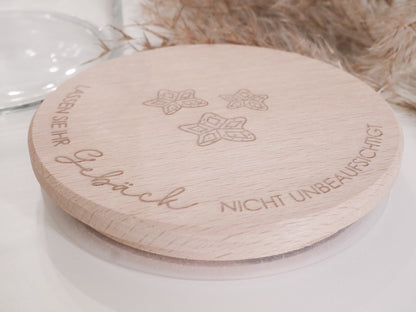 Handgefertigtes Vorratsglas mit graviertem Holzdeckel und Aufschrift „Lassen Sie Ihr Gebäck nicht unbeaufsichtigt“, dekoriert mit feinen Schneeflocken. Ein liebevolles Detail für jede Küche – natürlich, stilvoll und von Leo & Lu.