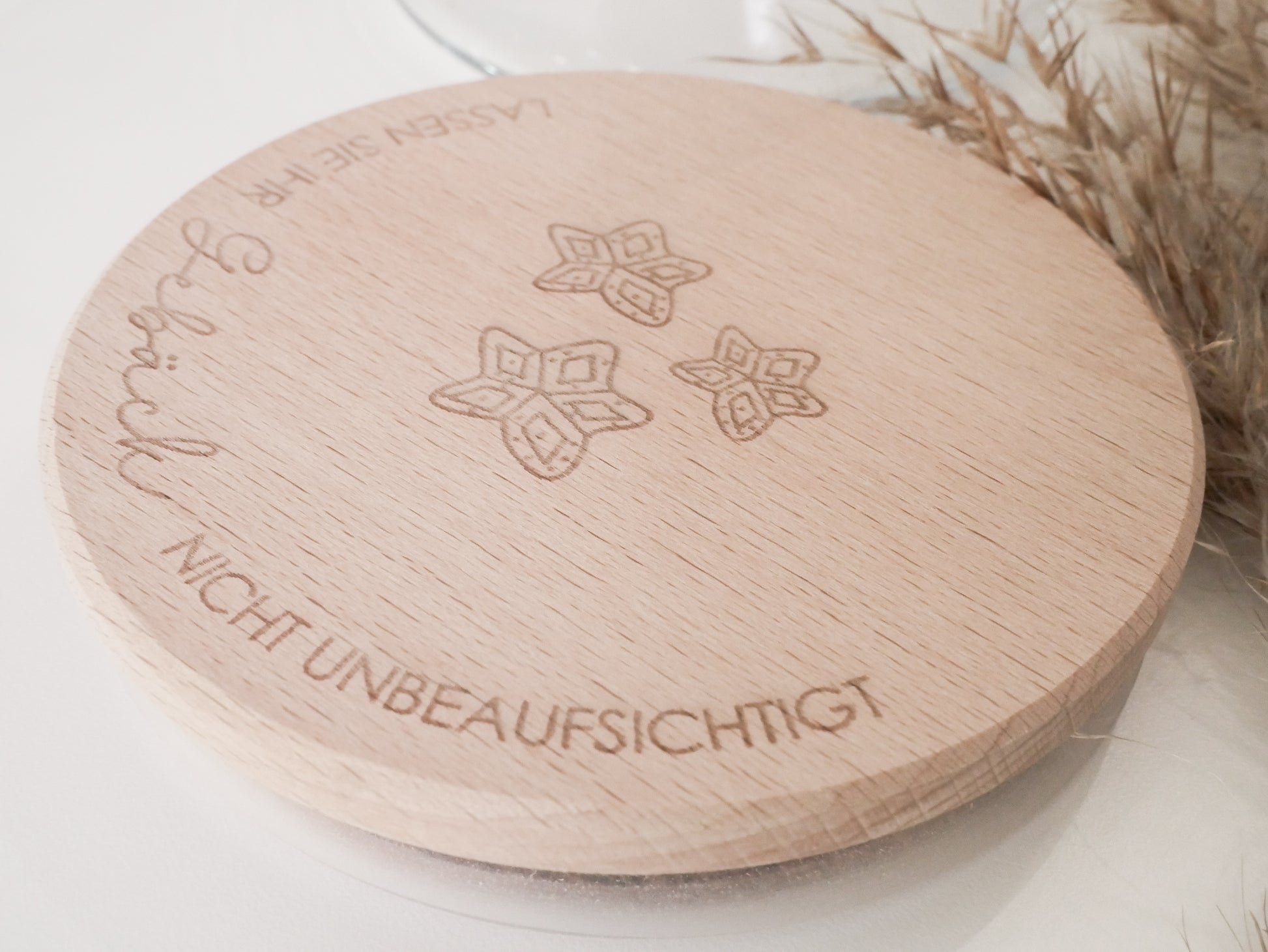 Handgefertigtes Vorratsglas mit graviertem Holzdeckel und Aufschrift „Lassen Sie Ihr Gebäck nicht unbeaufsichtigt“, dekoriert mit feinen Schneeflocken. Ein liebevolles Detail für jede Küche – natürlich, stilvoll und von Leo & Lu.