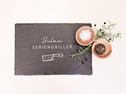Schieferplatte mit personalisiertem Namen hier in dem Beispiel Julian und darunter die Bezeichnung Seriengriller und ein Messer