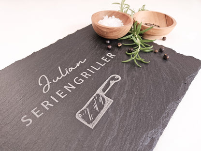 Schieferplatte mit personalisiertem Namen hier in dem Beispiel Julian und darunter die Bezeichnung Seriengriller und ein Messer