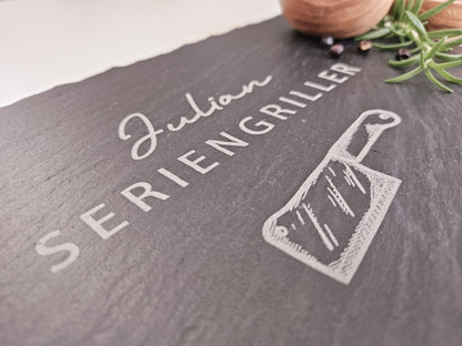Schieferplatte mit personalisiertem Namen hier in dem Beispiel Julian und darunter die Bezeichnung Seriengriller und ein Messer