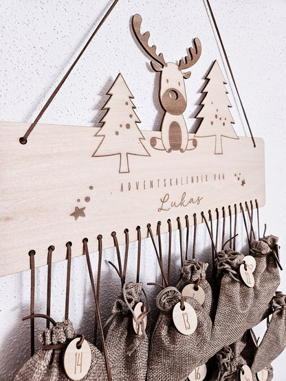 Personalisierter Holz-Adventskalender mit Rentier und Tannenbäumen, Gravur „Adventskalender von Lukas“. Mit 24 nummerierten Holzanhängern zum Aufhängen kleiner Geschenke. Nachhaltige Weihnachtsdekoration für Kinder und Familien.