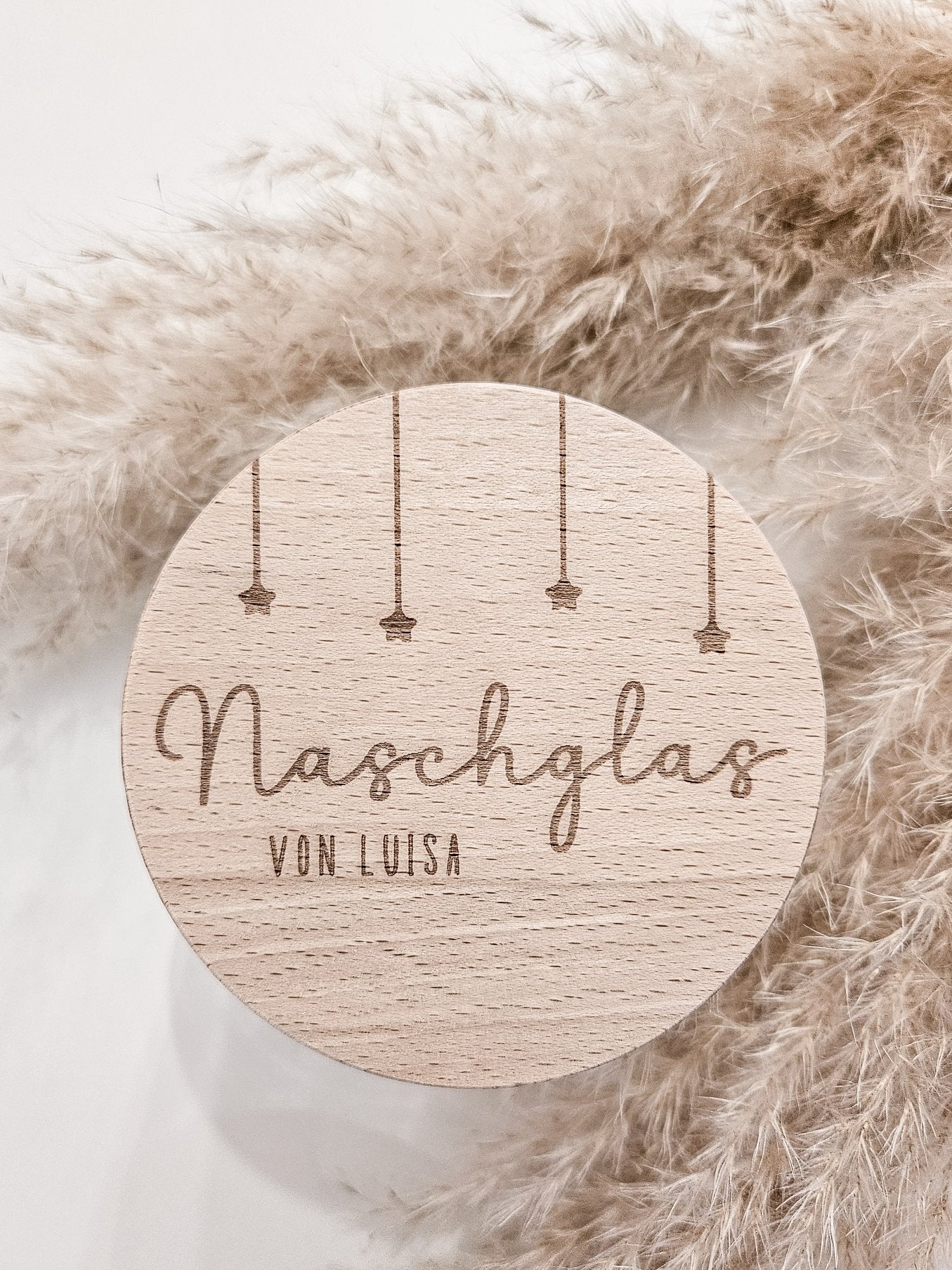 Runder Holzdeckel mit graviertem Schriftzug „Naschglas von Luisa“ und Sternanhängern, auf Glas liegend – personalisierte Geschenkidee.