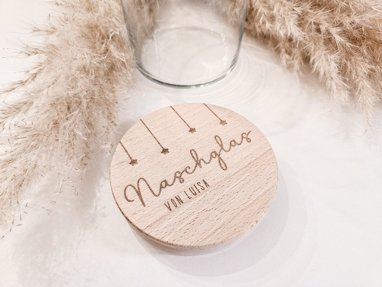 Runder Holzdeckel mit graviertem Schriftzug „Naschglas von Luisa“ und Sternanhängern, auf Glas liegend – personalisierte Geschenkidee.