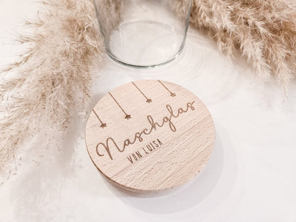 Runder Holzdeckel mit graviertem Schriftzug „Naschglas von Luisa“ und Sternanhängern, auf Glas liegend – personalisierte Geschenkidee.