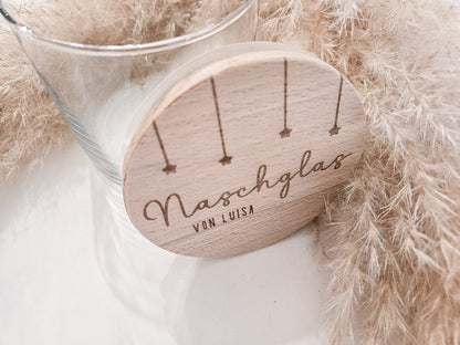 Runder Holzdeckel mit graviertem Schriftzug „Naschglas von Luisa“ und Sternanhängern, auf Glas liegend – personalisierte Geschenkidee.