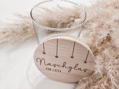 Runder Holzdeckel mit graviertem Schriftzug „Naschglas von Luisa“ und Sternanhängern, auf Glas liegend – personalisierte Geschenkidee.