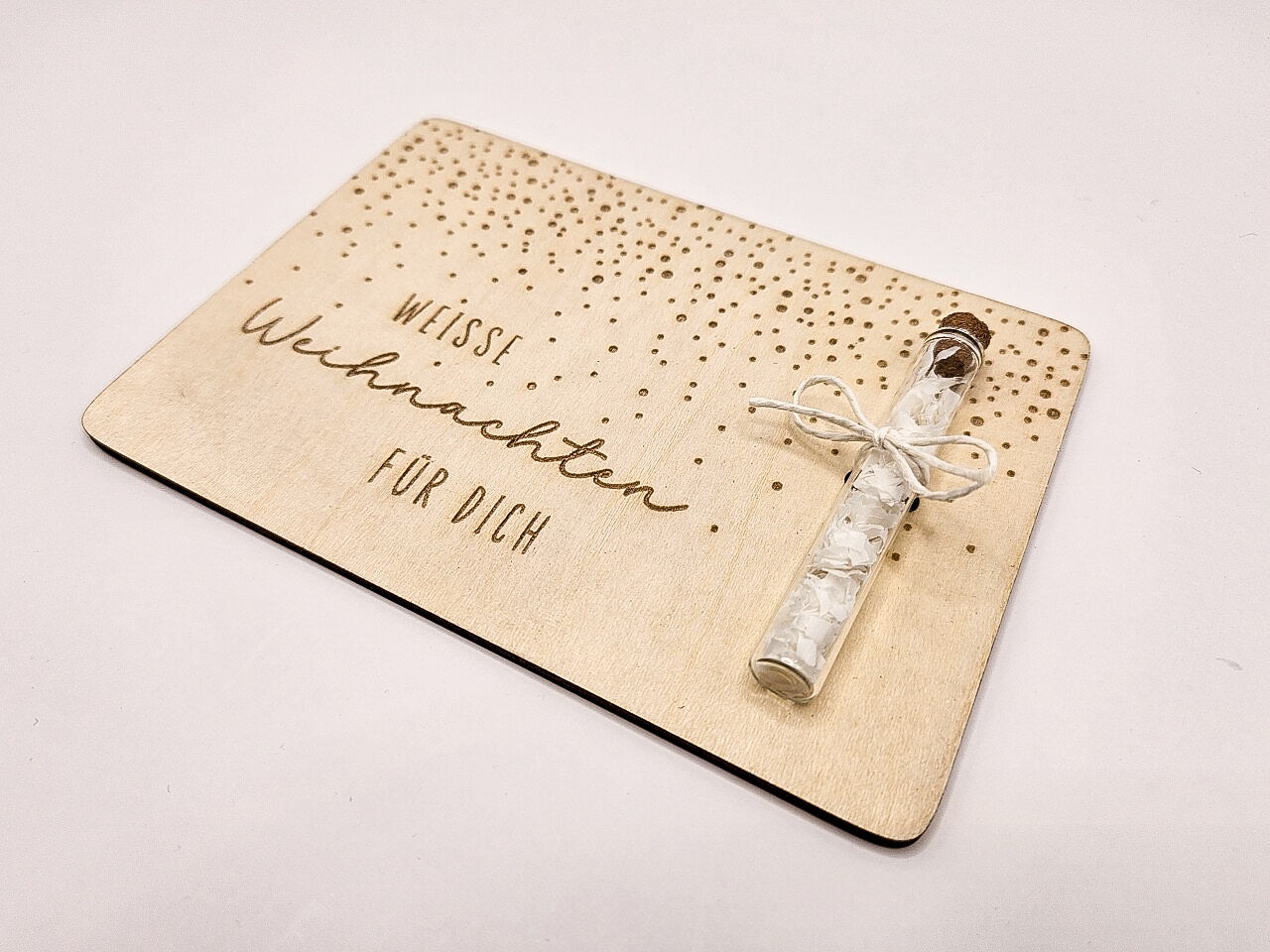 Holzkarte „Weiße Weihnachten“ mit Glasröhrchen, Gravur und winterlicher Deko im skandinavischen Stil auf hellem Holztisch