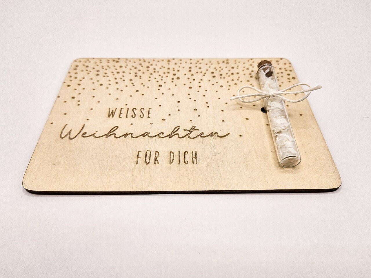 Holzkarte „Weiße Weihnachten“ mit Glasröhrchen, Gravur und winterlicher Deko im skandinavischen Stil auf hellem Holztisch