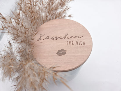 Dekoratives Geschenkglas aus klarem Glas mit hochwertigem Buchenholzdeckel und feiner Gravur „Küsschen für dich“. Das minimalistische Design im Scandi-Stil macht das Glas zu einer liebevollen Geschenkidee für Valentinstag, Muttertag, Geburtstag oder als kleine Aufmerksamkeit für Herzensmenschen. Ideal zum individuellen Befüllen mit Süßigkeiten oder Botschaften. Die abgebildeten Süßigkeiten sind Dekoration und nicht im Lieferumfang enthalten.
