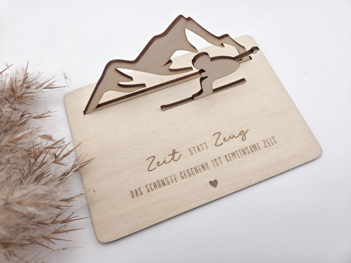 Geschenkkarte aus Holz mit filigranem Skifahrer vor einer Bergkulisse und der Gravur „Zeit statt Zeug – Das schönste Geschenk ist gemeinsame Zeit“. Die besondere Holzkarte eignet sich ideal als Geldgeschenk für Skiurlaub, Skitag oder Winterurlaub sowie als Gutschein für gemeinsame Erlebnisse. Eine kreative Geschenkidee für Skifahrer, Bergliebhaber, Paare, Freunde und Familie zu Geburtstag, Weihnachten oder Jahrestag – natürlich und liebevoll gestaltet.