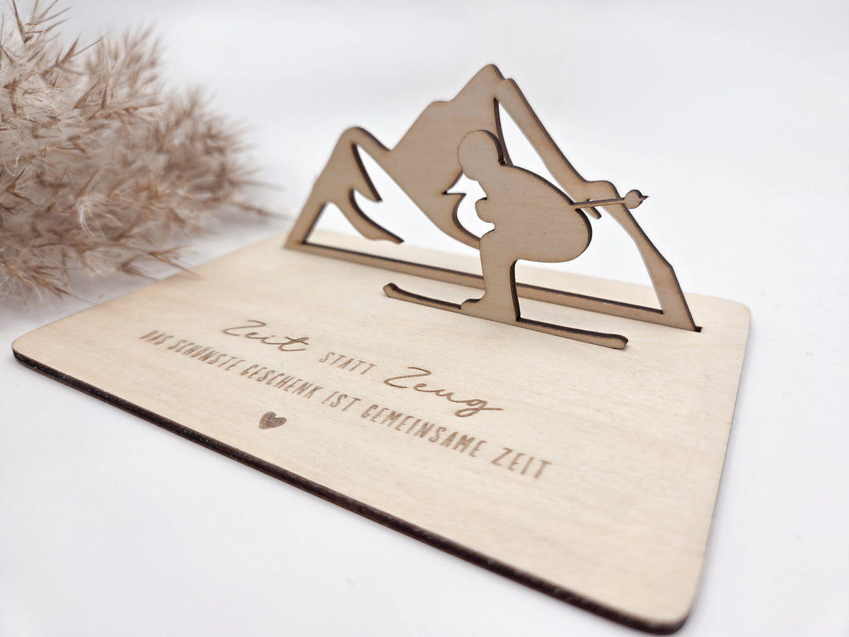 Geschenkkarte aus Holz mit filigranem Skifahrer vor einer Bergkulisse und der Gravur „Zeit statt Zeug – Das schönste Geschenk ist gemeinsame Zeit“. Die besondere Holzkarte eignet sich ideal als Geldgeschenk für Skiurlaub, Skitag oder Winterurlaub sowie als Gutschein für gemeinsame Erlebnisse. Eine kreative Geschenkidee für Skifahrer, Bergliebhaber, Paare, Freunde und Familie zu Geburtstag, Weihnachten oder Jahrestag – natürlich und liebevoll gestaltet.
