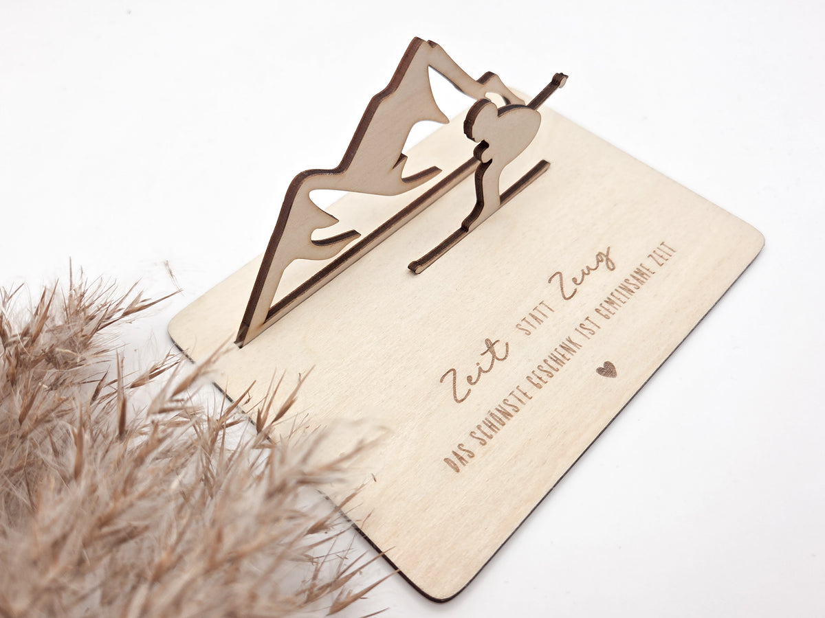 Geschenkkarte aus Holz mit filigranem Skifahrer vor einer Bergkulisse und der Gravur „Zeit statt Zeug – Das schönste Geschenk ist gemeinsame Zeit“. Die besondere Holzkarte eignet sich ideal als Geldgeschenk für Skiurlaub, Skitag oder Winterurlaub sowie als Gutschein für gemeinsame Erlebnisse. Eine kreative Geschenkidee für Skifahrer, Bergliebhaber, Paare, Freunde und Familie zu Geburtstag, Weihnachten oder Jahrestag – natürlich und liebevoll gestaltet.