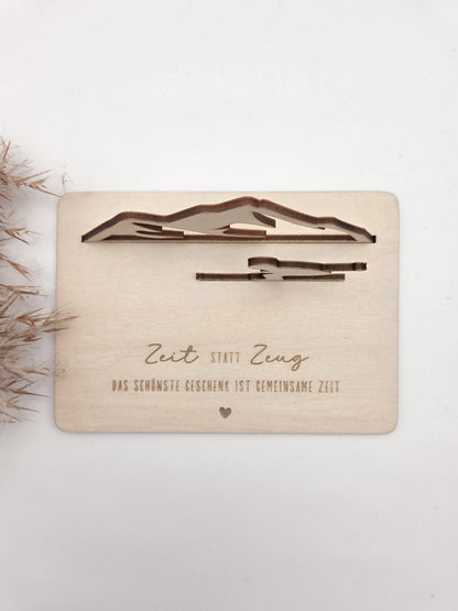 Geschenkkarte aus Holz mit filigranem Skifahrer vor einer Bergkulisse und der Gravur „Zeit statt Zeug – Das schönste Geschenk ist gemeinsame Zeit“. Die besondere Holzkarte eignet sich ideal als Geldgeschenk für Skiurlaub, Skitag oder Winterurlaub sowie als Gutschein für gemeinsame Erlebnisse. Eine kreative Geschenkidee für Skifahrer, Bergliebhaber, Paare, Freunde und Familie zu Geburtstag, Weihnachten oder Jahrestag – natürlich und liebevoll gestaltet.