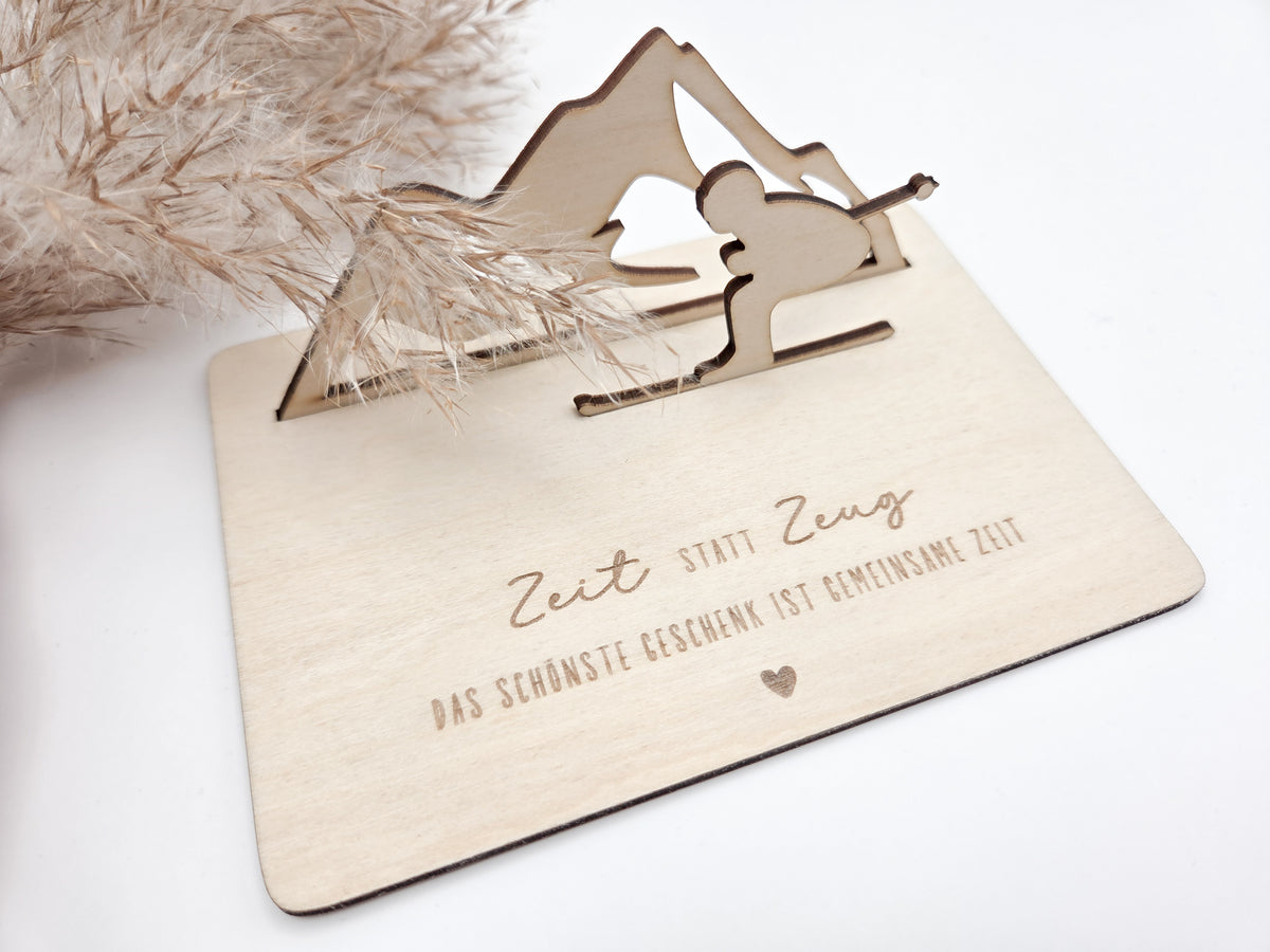Geschenkkarte aus Holz mit filigranem Skifahrer vor einer Bergkulisse und der Gravur „Zeit statt Zeug – Das schönste Geschenk ist gemeinsame Zeit“. Die besondere Holzkarte eignet sich ideal als Geldgeschenk für Skiurlaub, Skitag oder Winterurlaub sowie als Gutschein für gemeinsame Erlebnisse. Eine kreative Geschenkidee für Skifahrer, Bergliebhaber, Paare, Freunde und Familie zu Geburtstag, Weihnachten oder Jahrestag – natürlich und liebevoll gestaltet.