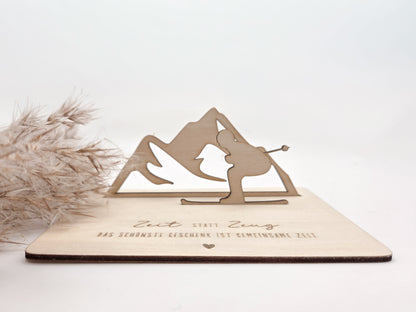 Geschenkkarte aus Holz mit filigranem Skifahrer vor einer Bergkulisse und der Gravur „Zeit statt Zeug – Das schönste Geschenk ist gemeinsame Zeit“. Die besondere Holzkarte eignet sich ideal als Geldgeschenk für Skiurlaub, Skitag oder Winterurlaub sowie als Gutschein für gemeinsame Erlebnisse. Eine kreative Geschenkidee für Skifahrer, Bergliebhaber, Paare, Freunde und Familie zu Geburtstag, Weihnachten oder Jahrestag – natürlich und liebevoll gestaltet.