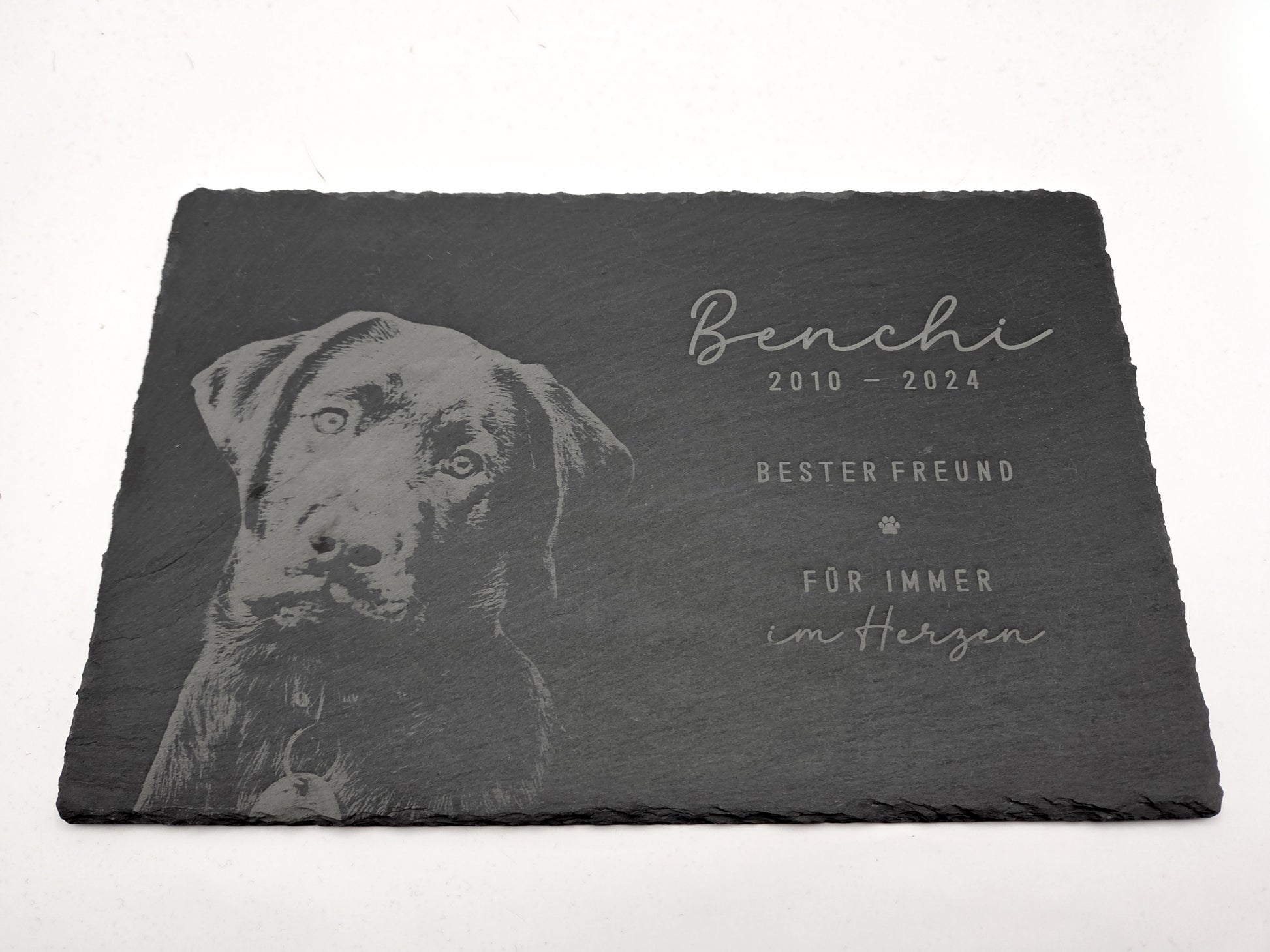Personalisierte Gedenkplatte für Haustiere aus echtem Naturschiefer mit Foto Gravur. Hochwertige Schieferplatte als Tier Gedenkstein und Grabplatte für Hund oder Katze, lasergraviert mit Haustierfoto, Name, Geburtsdatum, Sterbedatum und zwei individuellen Sprüchen. Natürliche Bruchkante, langlebig, UV- und wetterbeständig. Kein Druck, sondern dauerhafte Gravur im Stein. Ideal als Haustier Gedenkstein, Trauergeschenk und Erinnerung an ein verstorbenes Haustier.