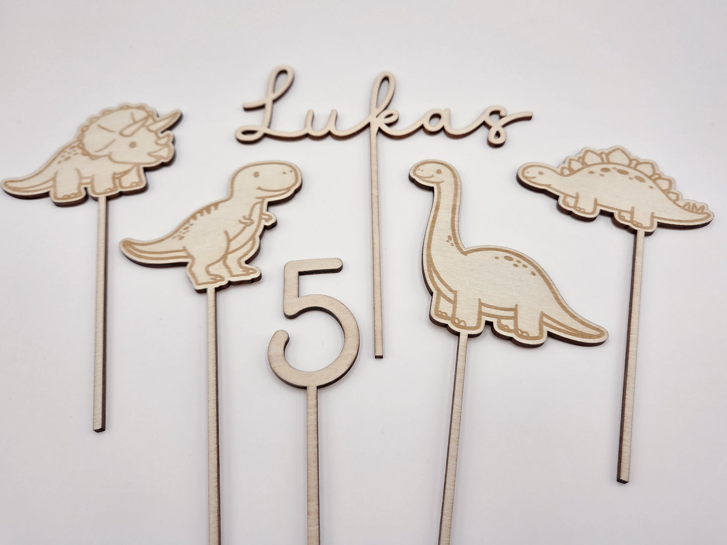 Dino Cake Topper personalisiert aus Holz mit Name und Alter für Dinosaurier Kindergeburtstag Junge. Tortendeko Dinosaurier Set mit Triceratops, T-Rex, Brachiosaurus und Stegosaurus, individueller Namensstecker und Zahl. Hochwertiger Holz Caketopper für Dino Party Deko, Geburtstagstorte Junge 3 4 5 6 Jahre, natürliche Tortendekoration für Naked Cake, Buttercremetorte oder Fondantkuchen. Personalisierte Geburtstagsdeko Holz kaufen bei leoundlu.de.