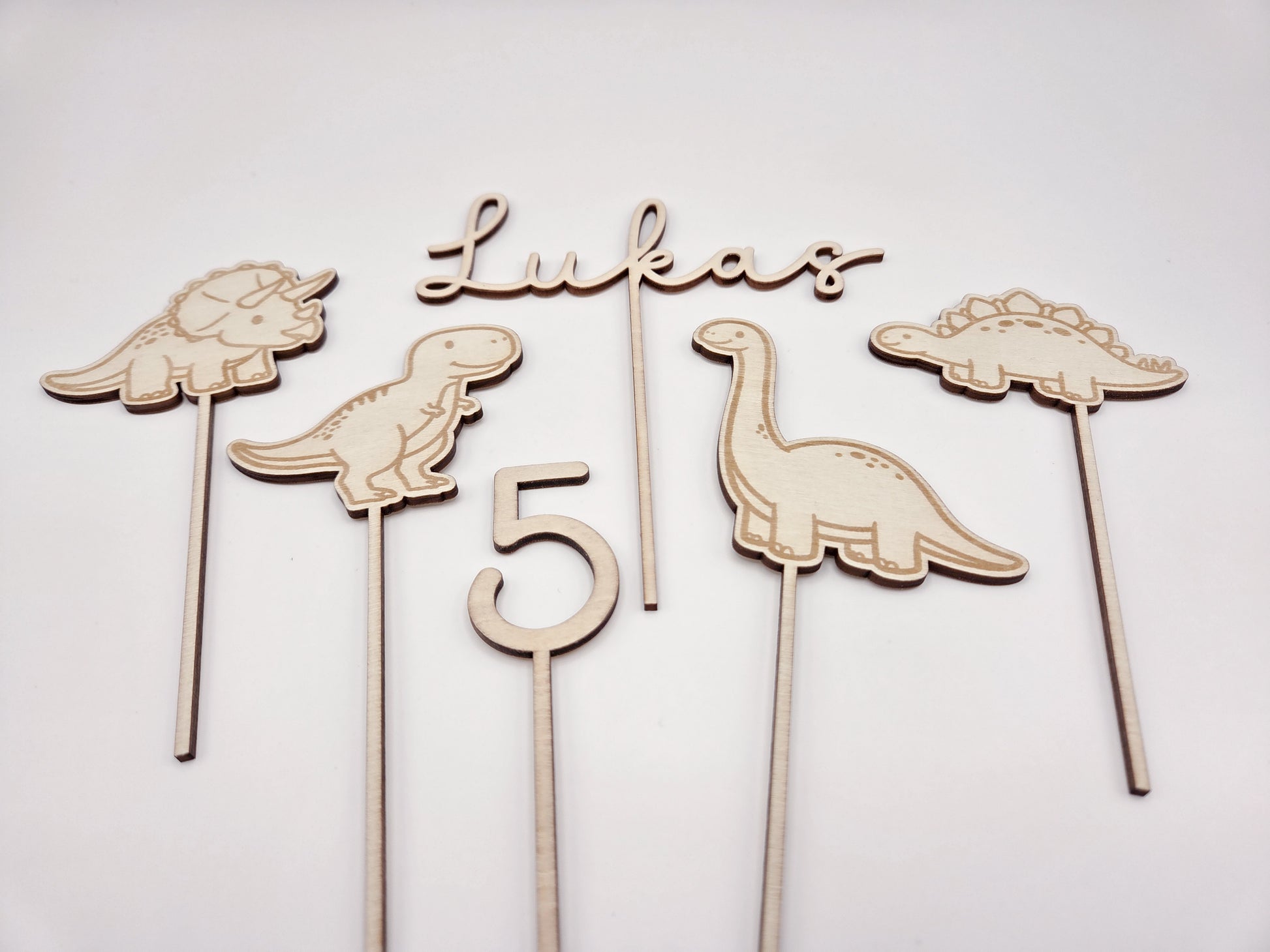 Dino Cake Topper personalisiert aus Holz mit Name und Alter für Dinosaurier Kindergeburtstag Junge. Tortendeko Dinosaurier Set mit Triceratops, T-Rex, Brachiosaurus und Stegosaurus, individueller Namensstecker und Zahl. Hochwertiger Holz Caketopper für Dino Party Deko, Geburtstagstorte Junge 3 4 5 6 Jahre, natürliche Tortendekoration für Naked Cake, Buttercremetorte oder Fondantkuchen. Personalisierte Geburtstagsdeko Holz kaufen bei leoundlu.de.
