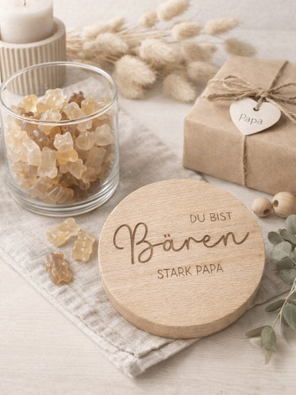 Geschenkglas mit graviertem Holzdeckel für Papa, gefüllt mit hellen Gummibärchen im skandinavischen Stil dekoriert. Der Deckel trägt die liebevolle Gravur „Du bist Bären stark Papa“ mit Herzmotiv. Perfekte Geschenkidee zum Vatertag, Geburtstag oder als kleines Dankeschön für den besten Papa. Modernes, minimalistisches Setting mit Naturmaterialien wie Holz, Trockenblumen und Kerze sorgt für eine warme, hochwertige Präsentation und macht dieses personalisierte Papa Geschenk besonders emotional und einzigartig
