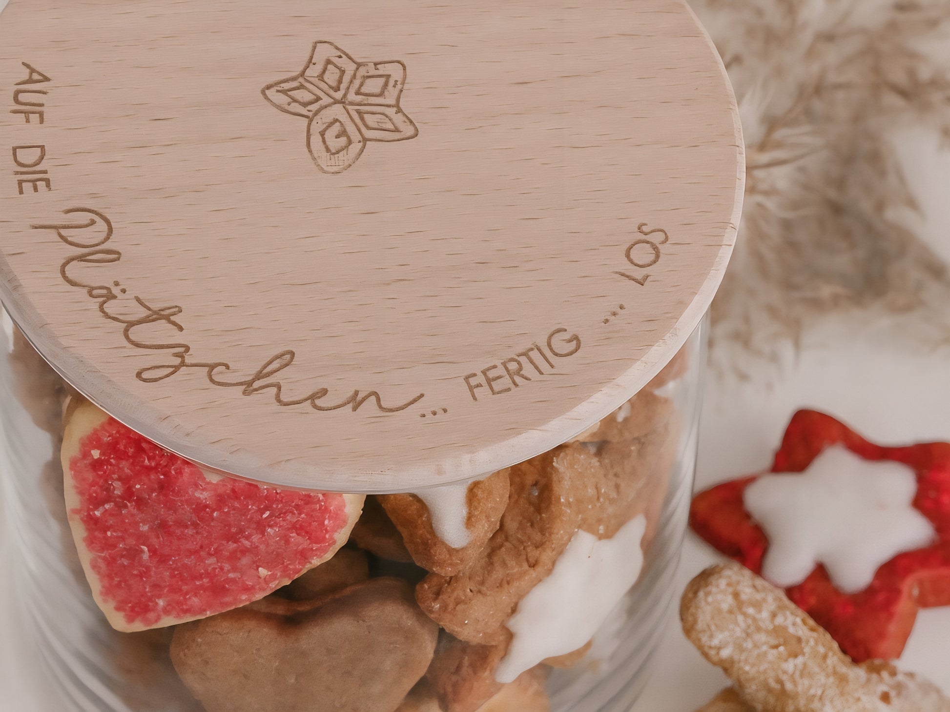 Glas mit Holzdeckel und Gravur „Auf die Plätzchen … fertig … los“ gefüllt mit Weihnachtsplätzchen. Daneben liegen Zimtsterne und Vanillekipferl auf hellem Hintergrund – stimmungsvolles, nordisch-cleanes Weihnachtsmotiv.