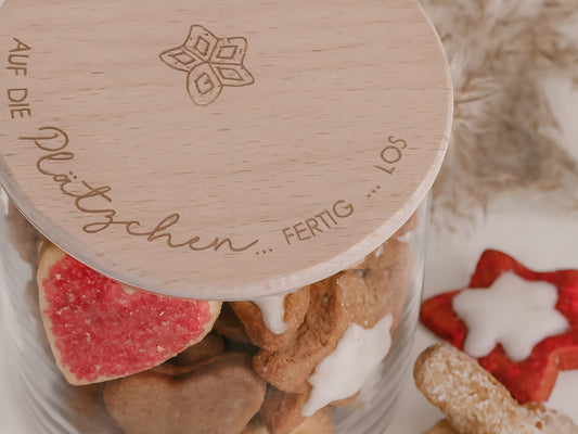 Glas mit Holzdeckel und Gravur „Auf die Plätzchen … fertig … los“ gefüllt mit Weihnachtsplätzchen. Daneben liegen Zimtsterne und Vanillekipferl auf hellem Hintergrund – stimmungsvolles, nordisch-cleanes Weihnachtsmotiv.