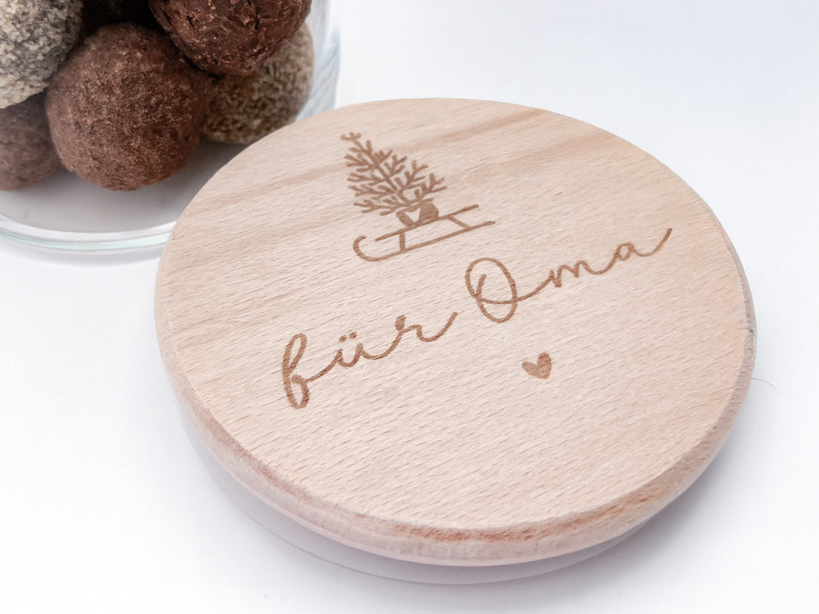 „Personalisierbares Geschenkglas mit hellem Holzdeckel, graviert mit Weihnachtsbaum auf Schlitten und Schriftzug ‚für Oma‘. Skandi, natürlich, handgemacht – Geschenkidee zu Weihnachten.“