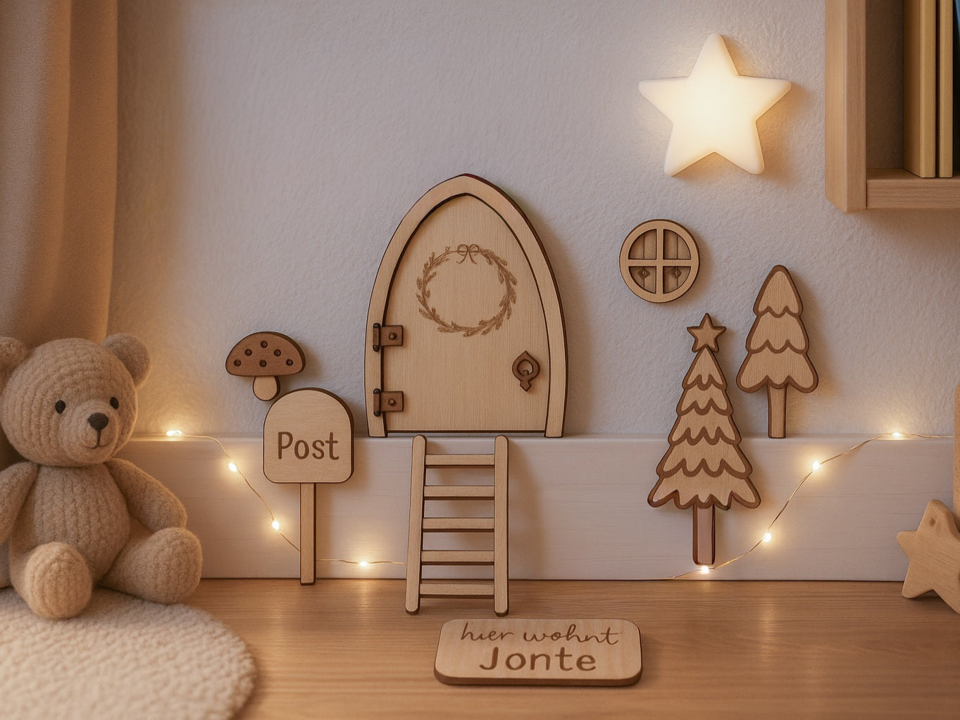 Personalisierbare Holz-Wichteltür mit Leiter, Briefkasten, Pilz und zwei Tannenbäumen an einer weißen Sockelleiste im Kinderzimmer, auf hellblauer Wand mit weißen Punkten montiert.