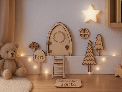 Personalisierbare Holz-Wichteltür mit Leiter, Briefkasten, Pilz und zwei Tannenbäumen an einer weißen Sockelleiste im Kinderzimmer, auf hellblauer Wand mit weißen Punkten montiert.