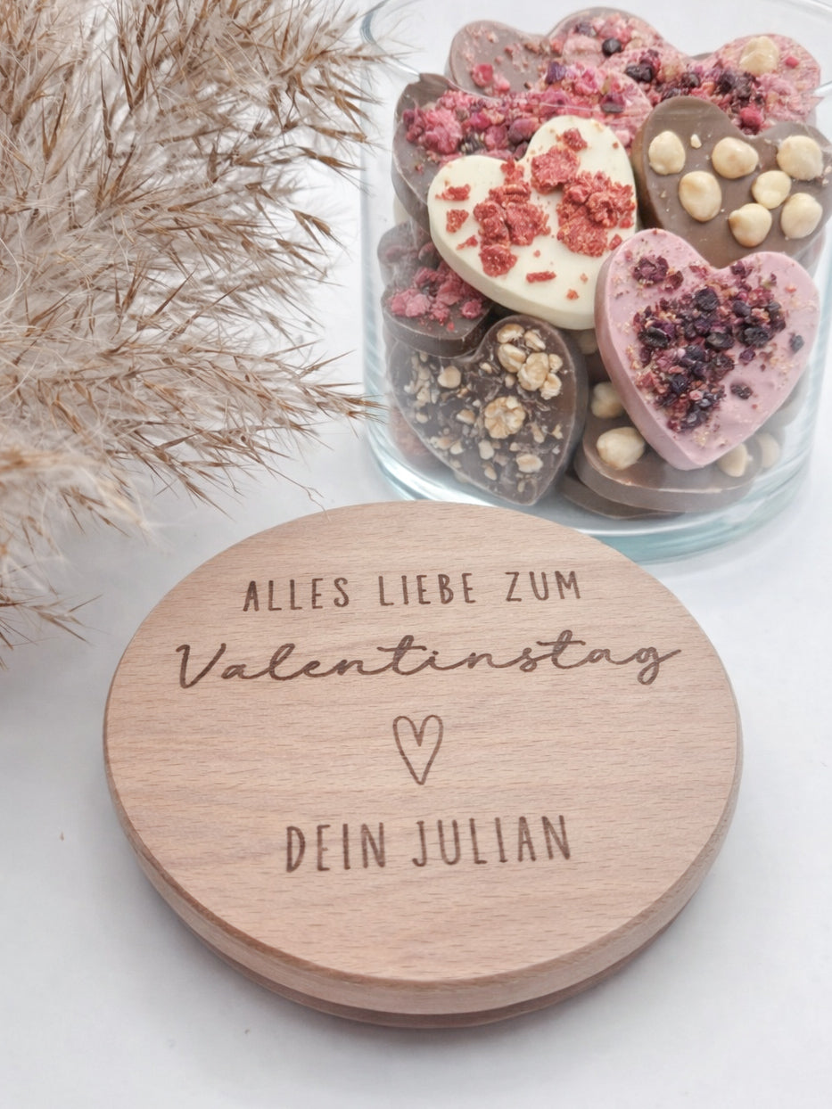 Personalisiertes Geschenkglas zum Valentinstag mit graviertem Holzdeckel und individueller Namensgravur. Hochwertiges Glas gefüllt mit Schokoladenherzen in Rosa, Weiß und Vollmilch, dekorativ angerichtet. Romantisches Valentinstagsgeschenk für Freundin, Geschenk für Freund, Geschenk für Partner oder Ehemann. Personalisiertes Schokoladengeschenk mit Gravur, Liebesgeschenk personalisiert, Geschenkidee Valentinstag, Geschenk für Paare, liebevolle Aufmerksamkeit, handgemachtes Geschenk, hochwertig und einzigart