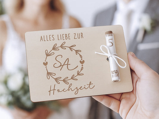 Holzkarte mit Gravur „Alles Liebe zur Hochzeit“, Initialen im Blumenkranz und Glasröhrchen als Geldgeschenk.