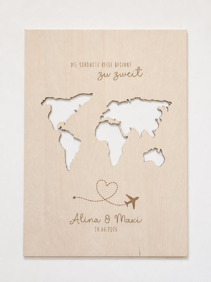 Personalisiertes Geldgeschenk zur Hochzeit aus hellem Holz mit filigraner Weltkarte und eingesteckten Euro-Geldscheinen hinter den Kontinenten. Die gravierte Aufschrift „Die schönste Reise beginnt zu zweit“ sowie die Namen des Brautpaares und das Hochzeitsdatum machen dieses Hochzeitsgeschenk zu einer besonderen Erinnerung. Das Holzbild steht in einer romantischen Hochzeitskulisse mit weißen Rosen, Kerzenlicht, Eheringen und eleganter Tischdekoration. Perfekt als Geldgeschenk für Flitterwochen, Reisekasse o