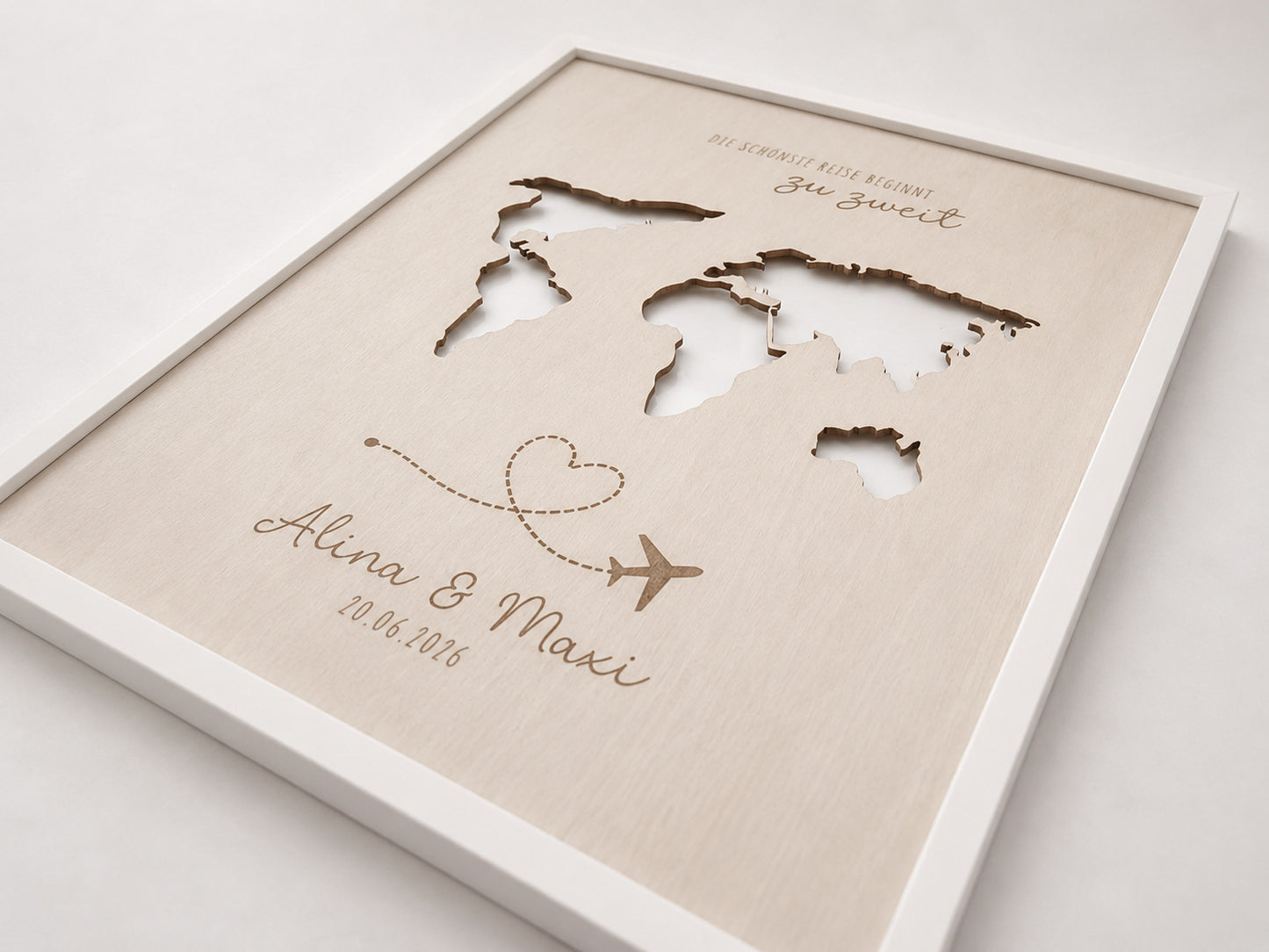 Personalisiertes Geldgeschenk zur Hochzeit aus hellem Holz mit filigraner Weltkarte und eingesteckten Euro-Geldscheinen hinter den Kontinenten. Die gravierte Aufschrift „Die schönste Reise beginnt zu zweit“ sowie die Namen des Brautpaares und das Hochzeitsdatum machen dieses Hochzeitsgeschenk zu einer besonderen Erinnerung. Das Holzbild steht in einer romantischen Hochzeitskulisse mit weißen Rosen, Kerzenlicht, Eheringen und eleganter Tischdekoration. Perfekt als Geldgeschenk für Flitterwochen, Reisekasse o