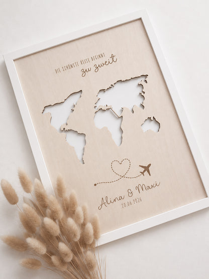 Personalisiertes Geldgeschenk zur Hochzeit aus hellem Holz mit filigraner Weltkarte und eingesteckten Euro-Geldscheinen hinter den Kontinenten. Die gravierte Aufschrift „Die schönste Reise beginnt zu zweit“ sowie die Namen des Brautpaares und das Hochzeitsdatum machen dieses Hochzeitsgeschenk zu einer besonderen Erinnerung. Das Holzbild steht in einer romantischen Hochzeitskulisse mit weißen Rosen, Kerzenlicht, Eheringen und eleganter Tischdekoration. Perfekt als Geldgeschenk für Flitterwochen, Reisekasse o