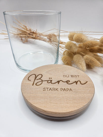 Geschenkglas mit graviertem Holzdeckel für Papa, gefüllt mit hellen Gummibärchen im skandinavischen Stil dekoriert. Der Deckel trägt die liebevolle Gravur „Du bist Bären stark Papa“ mit Herzmotiv. Perfekte Geschenkidee zum Vatertag, Geburtstag oder als kleines Dankeschön für den besten Papa. Modernes, minimalistisches Setting mit Naturmaterialien wie Holz, Trockenblumen und Kerze sorgt für eine warme, hochwertige Präsentation und macht dieses personalisierte Papa Geschenk besonders emotional und einzigartig