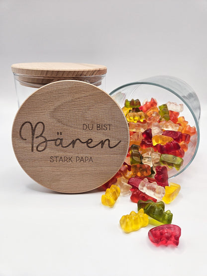 Geschenkglas mit graviertem Holzdeckel für Papa, gefüllt mit hellen Gummibärchen im skandinavischen Stil dekoriert. Der Deckel trägt die liebevolle Gravur „Du bist Bären stark Papa“ mit Herzmotiv. Perfekte Geschenkidee zum Vatertag, Geburtstag oder als kleines Dankeschön für den besten Papa. Modernes, minimalistisches Setting mit Naturmaterialien wie Holz, Trockenblumen und Kerze sorgt für eine warme, hochwertige Präsentation und macht dieses personalisierte Papa Geschenk besonders emotional und einzigartig