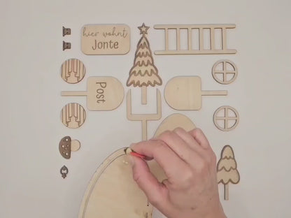 Personalisierbare Holz-Wichteltür mit Leiter, Briefkasten, Pilz und zwei Tannenbäumen an einer weißen Sockelleiste im Kinderzimmer, auf hellblauer Wand mit weißen Punkten montiert.