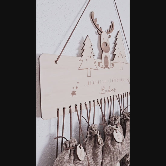 Personalisierter Holz-Adventskalender mit Rentier und Tannenbäumen, Gravur „Adventskalender von Lukas“. Mit 24 nummerierten Holzanhängern zum Aufhängen kleiner Geschenke. Nachhaltige Weihnachtsdekoration für Kinder und Familien.