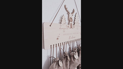 Personalisierter Holz-Adventskalender mit Rentier und Tannenbäumen, Gravur „Adventskalender von Lukas“. Mit 24 nummerierten Holzanhängern zum Aufhängen kleiner Geschenke. Nachhaltige Weihnachtsdekoration für Kinder und Familien.