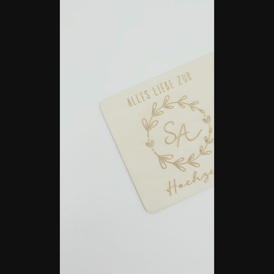 Holzkarte mit Gravur „Alles Liebe zur Hochzeit“, Initialen im Blumenkranz und Glasröhrchen als Geldgeschenk.
